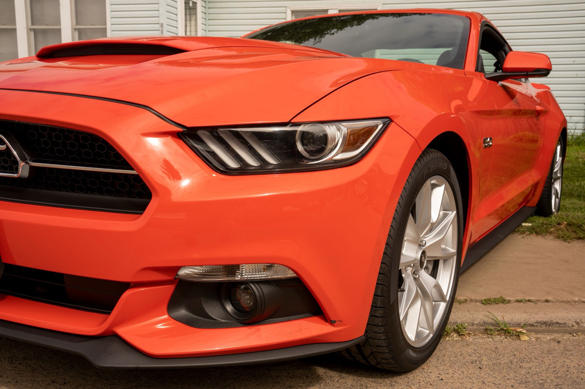 Close view of a freshly detailed orange coupe with a deep, even gloss across the hood and front wing
